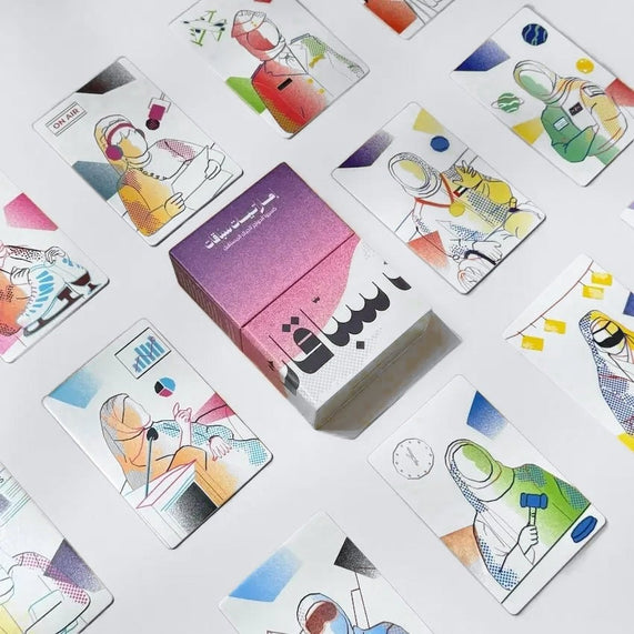 Illustrated pioneer cards scattered around closed pink and purple box, top view