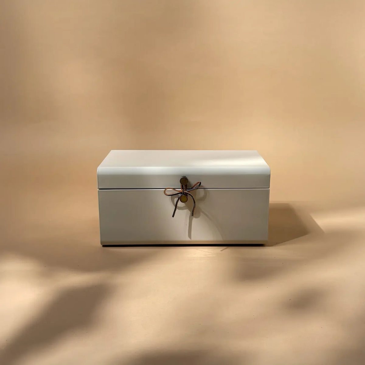 Almond milk galvanised steel trunk with vintage-style leather bow fastener, closed, front view