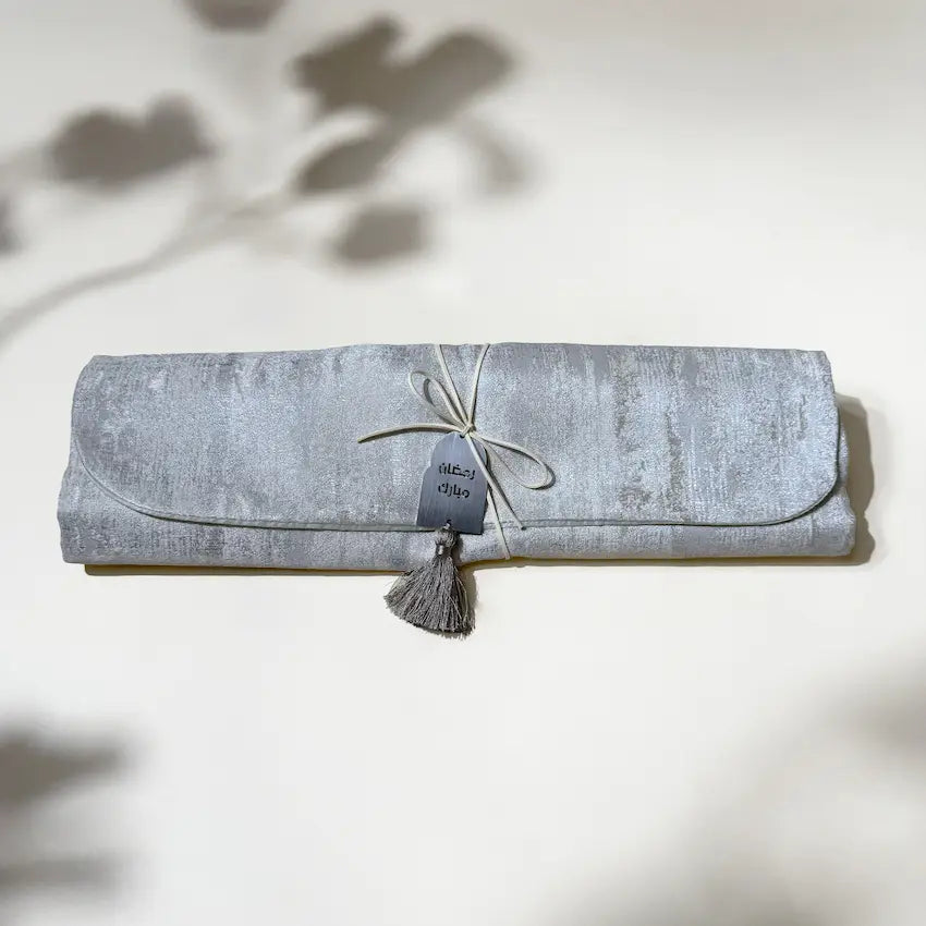 Rolled silver mukhawar pouch tied with cord, tassel and Ramadan Mubarak tag