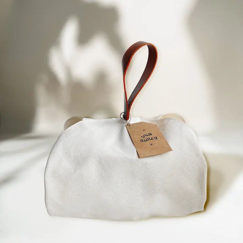 Cream fabric food wrap tied with tan leather handle and kraft gift tag