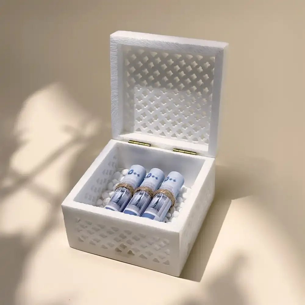 Open white marble cutout box showing rolled cash on white pebbles