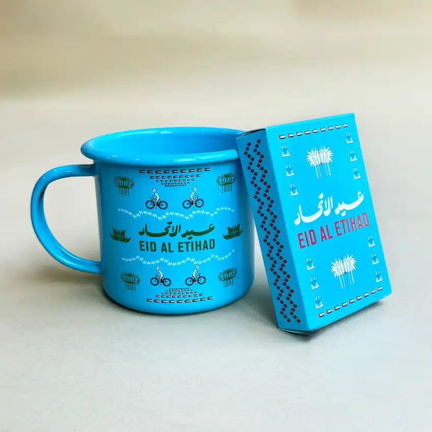 Sky blue enamel mug with cyclist print beside its National Day gift box
