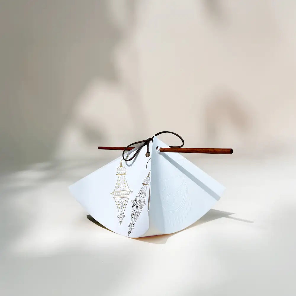 White bindle-style gift pouch with gold lantern motifs and wooden stick