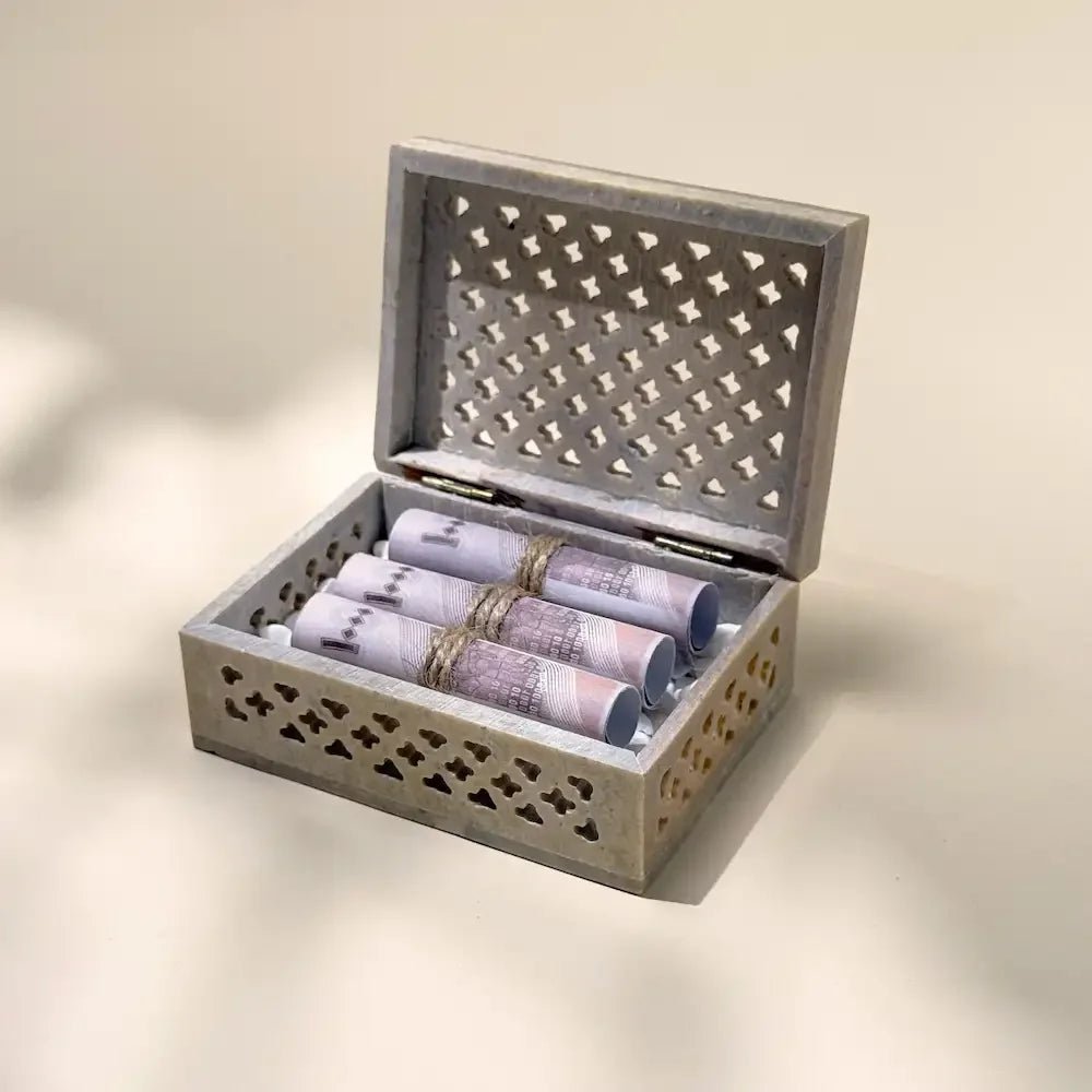 Open carved stone money box with rolled cash bundles tied in twine