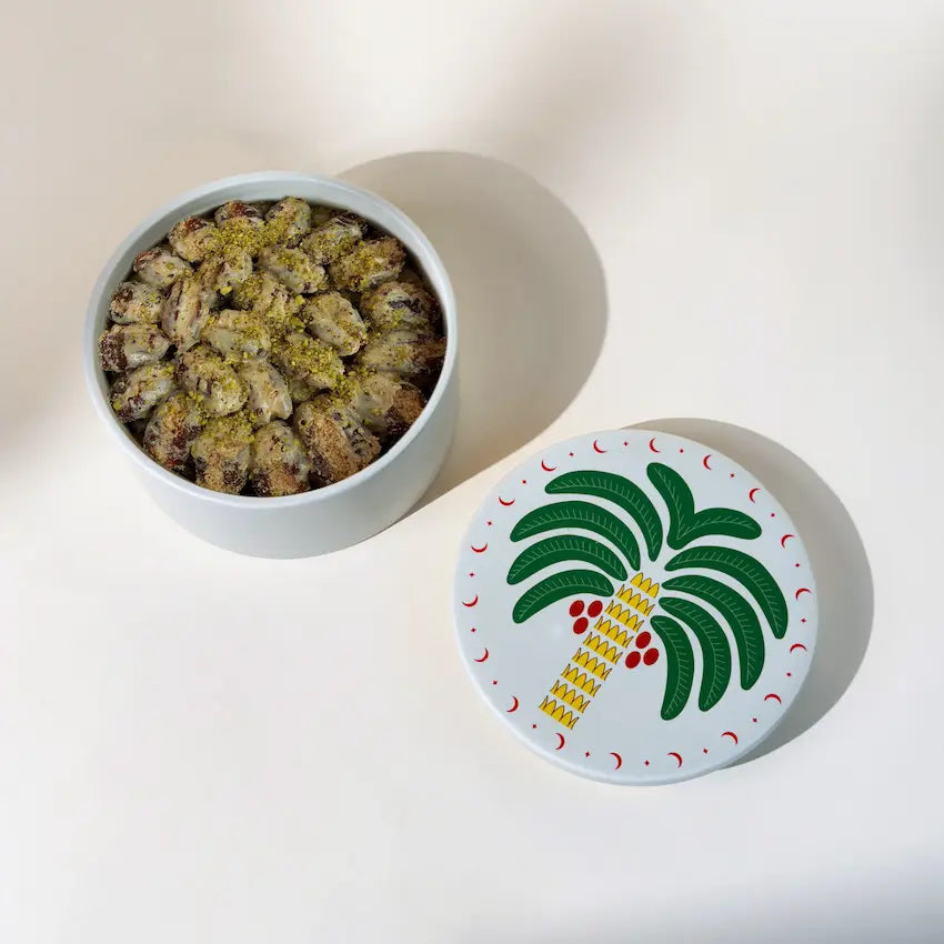 Open ceramic pot filled with Rahash dates beside palm tree printed lid