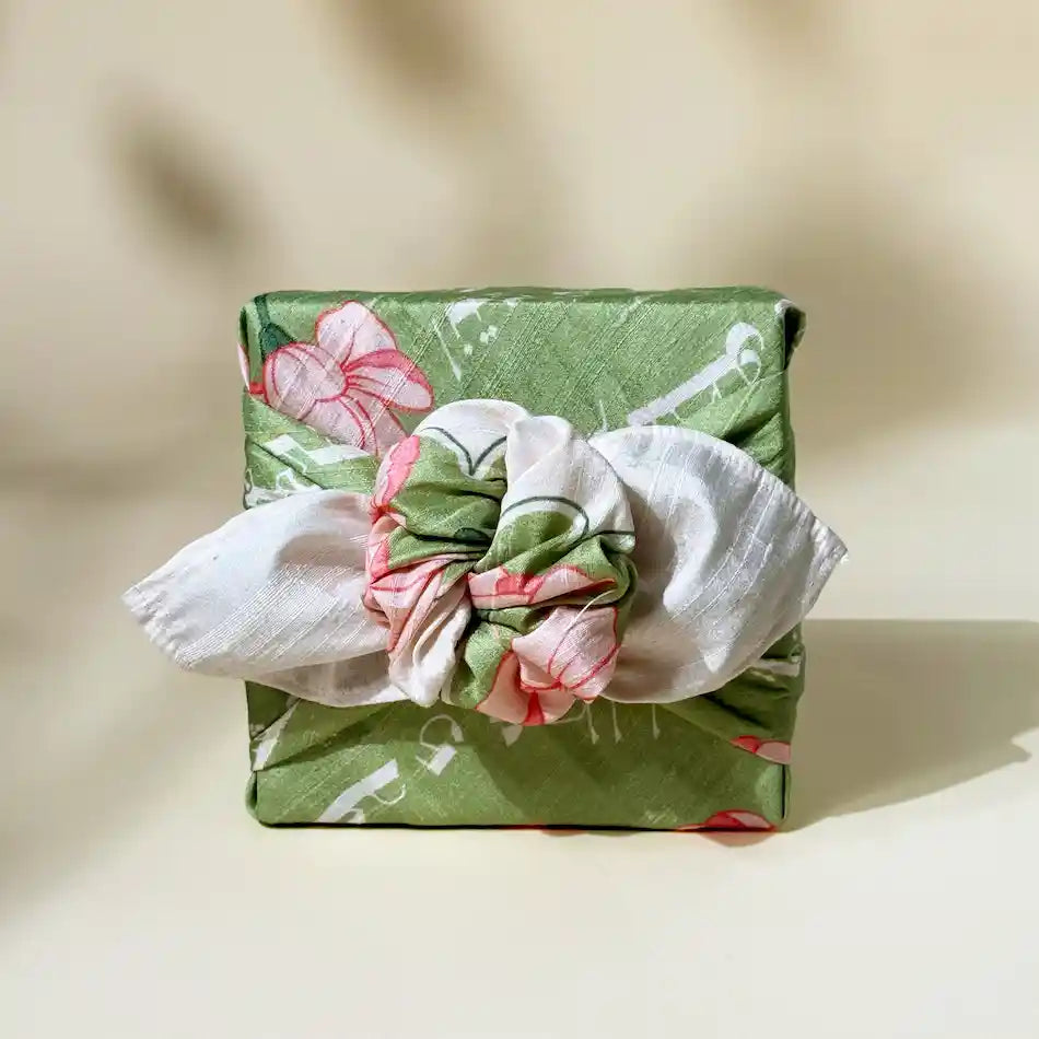 Gift box wrapped in green floral fabric, tied furoshiki-style with white knot