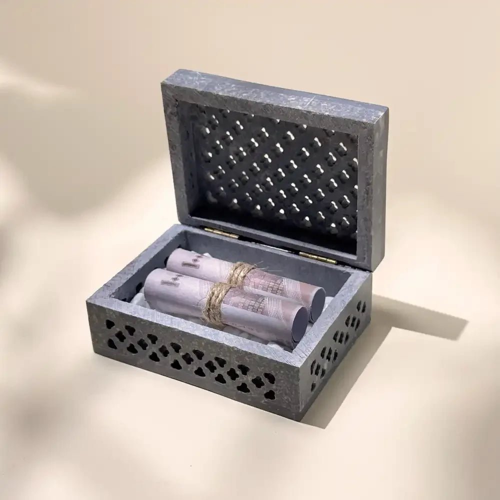 Open violet carved stone box revealing rolled cash tied with twine