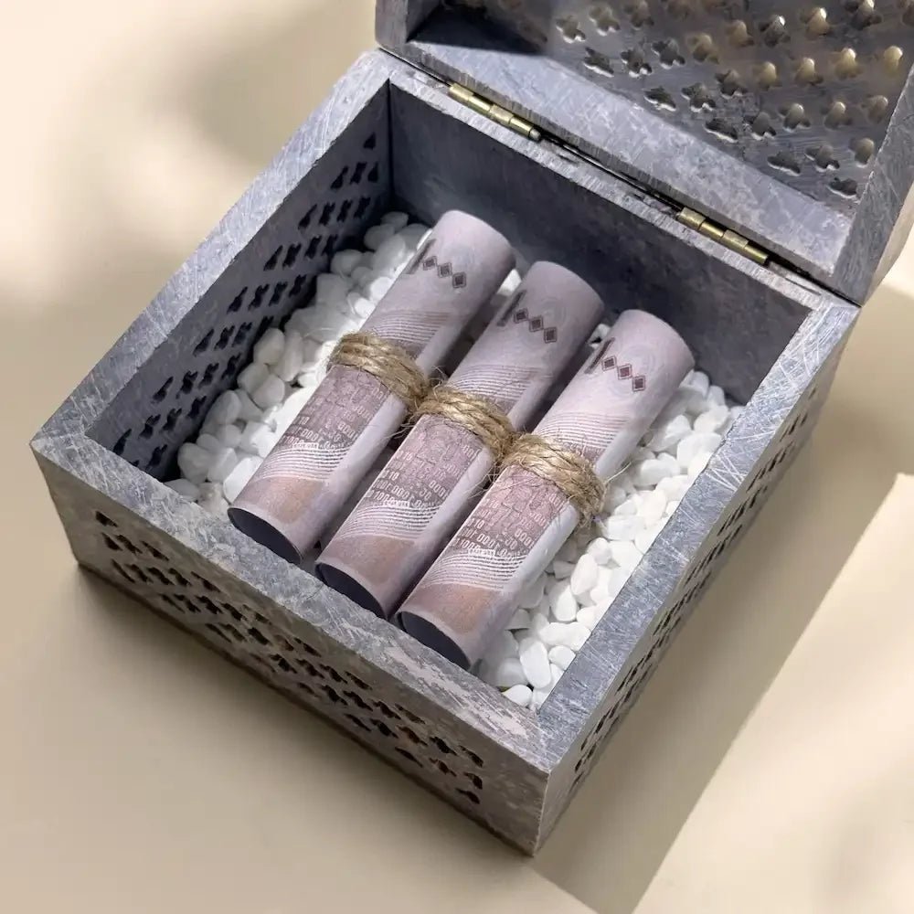Close-up of rolled cash tied with twine inside carved stone gift box