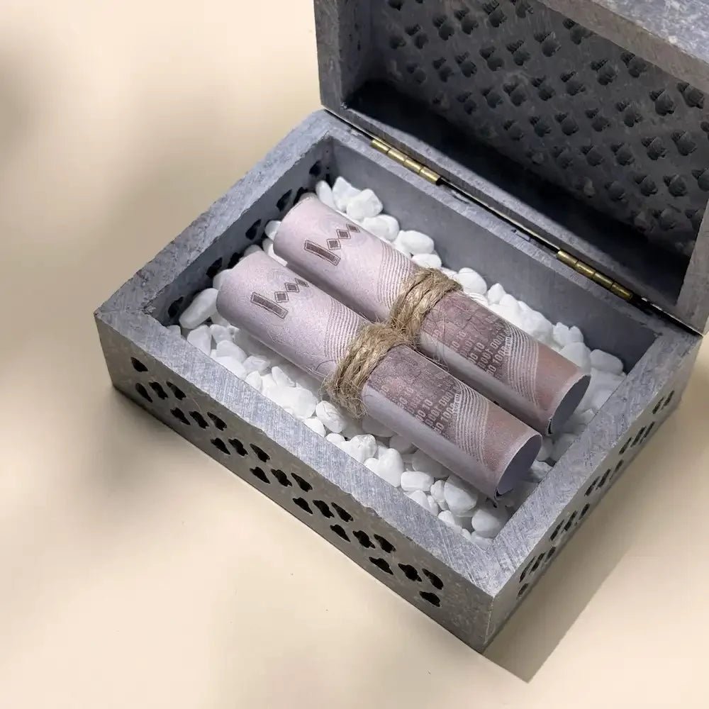 Close-up of rolled banknotes nestled in white pebbles inside stone box