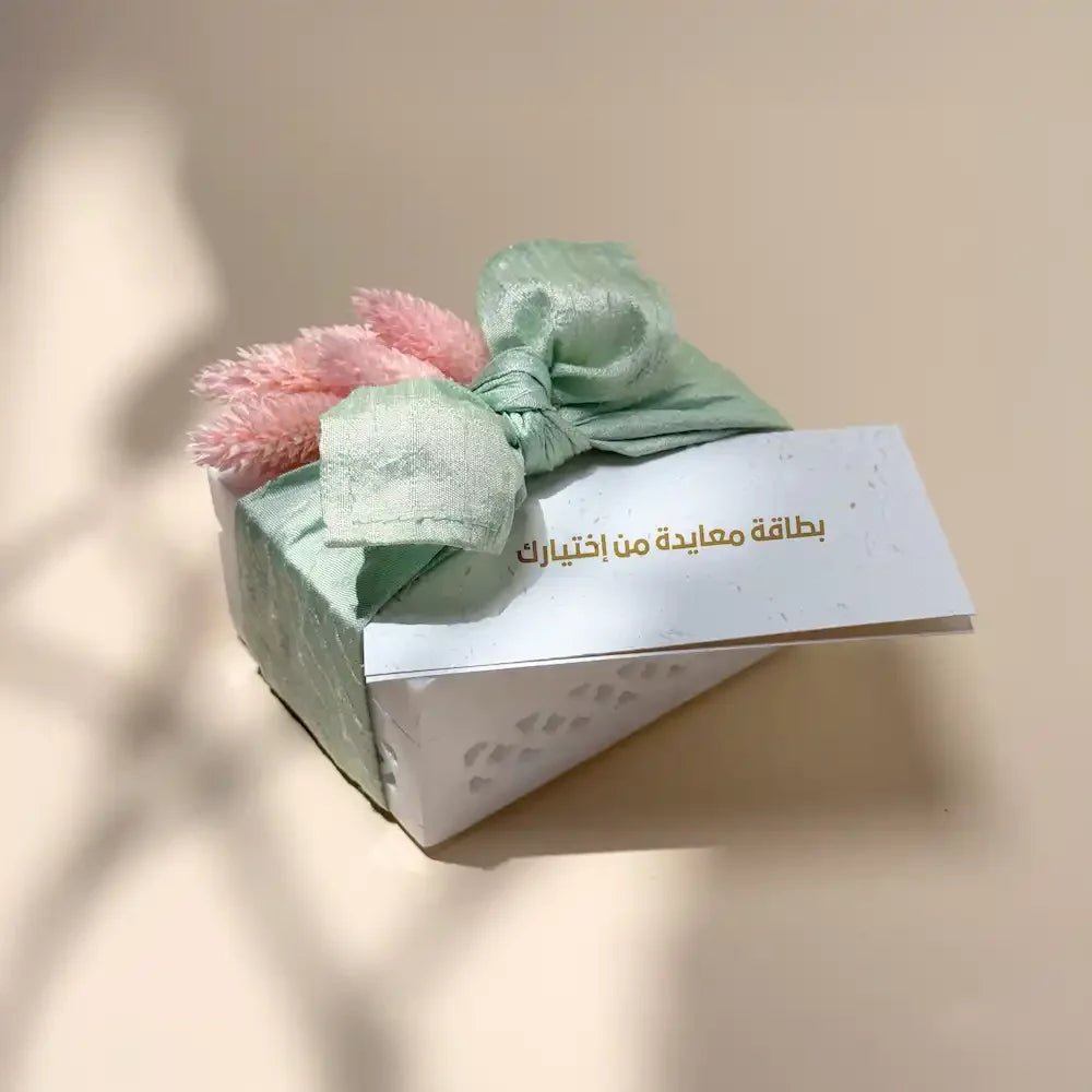 White marble-style cash box wrapped in mint green fabric bow with pink dried flowers