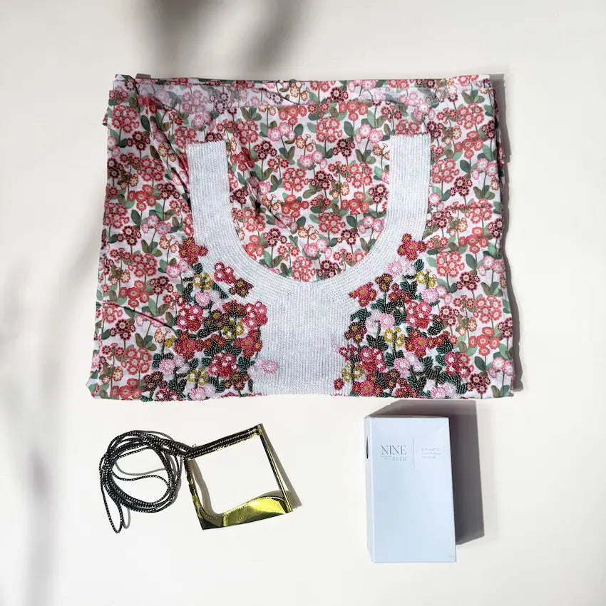 Floral mukhawer wrap unfolded beside gold tassel strap and perfume box
