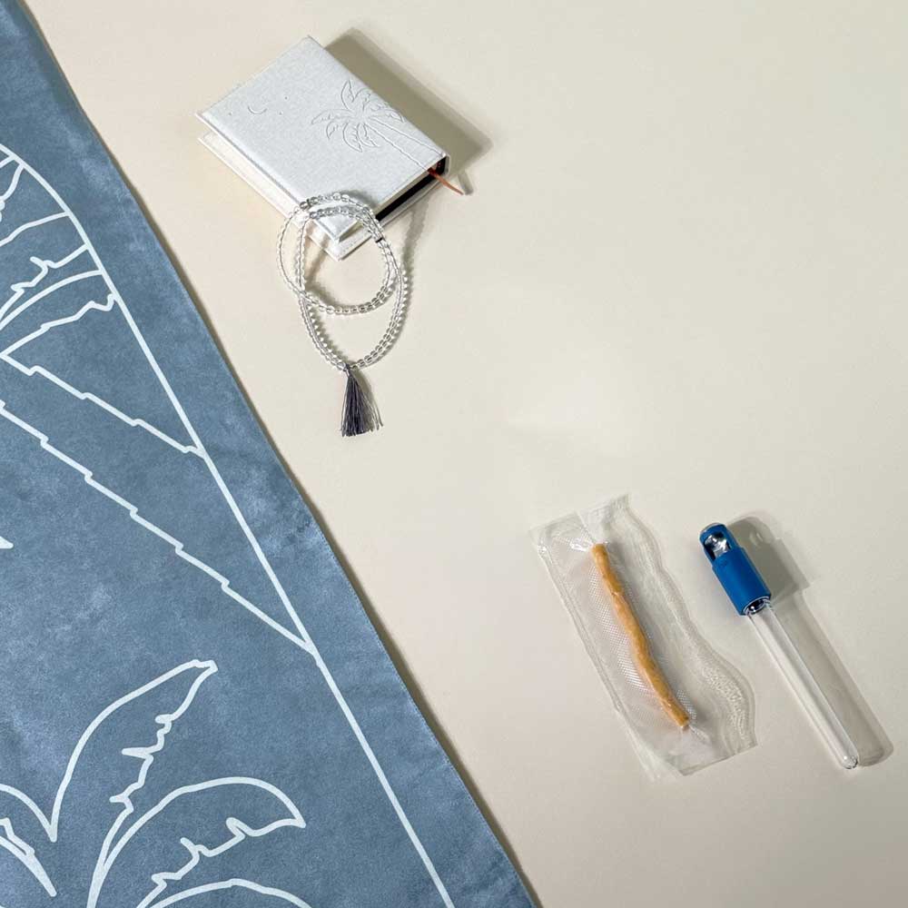 Close-up of prayer beads, embossed booklet and incense beside blue mat