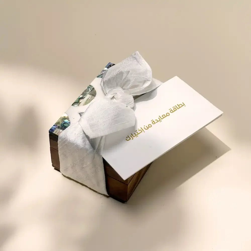 Rosewood cash box with abalone inlay, wrapped in off white fabric bow, greeting card on top