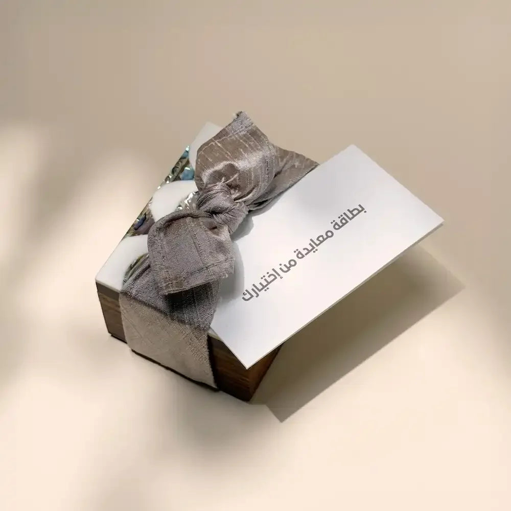 Rosewood mini box with abalone lid wrapped in taupe fabric bow, greeting card on top