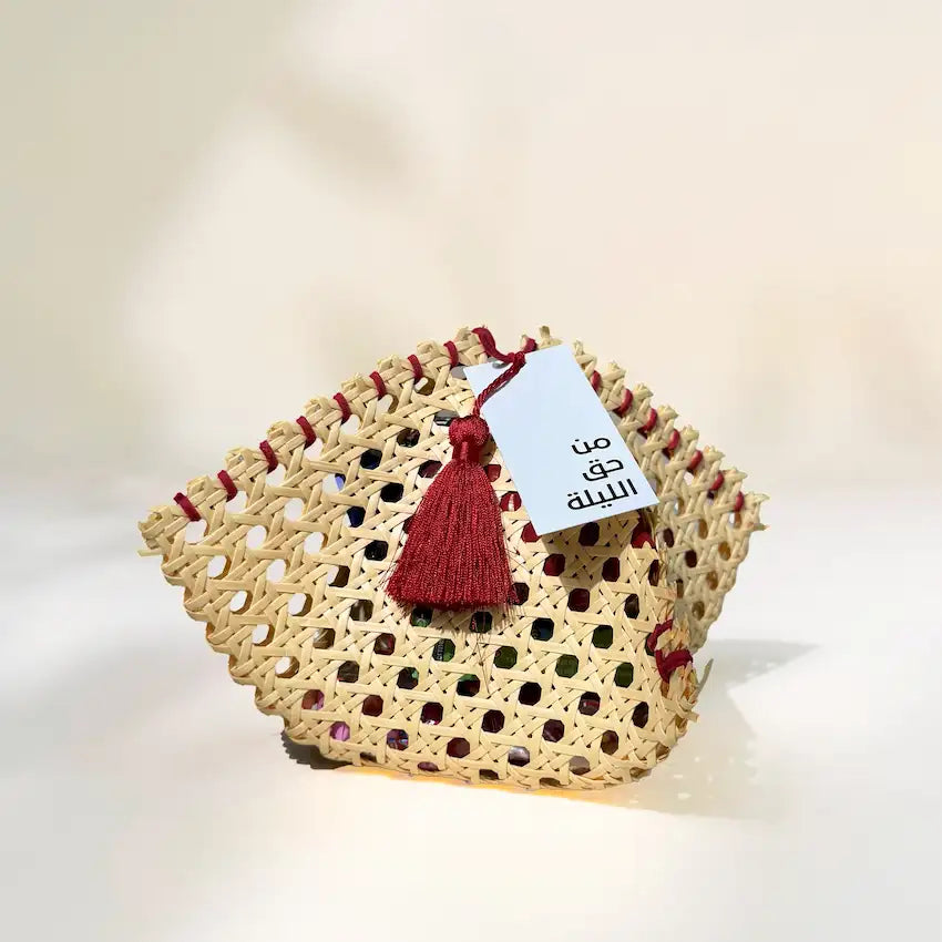 Woven rattan pouch with red tassel and Haq Al Laila tag, front angle