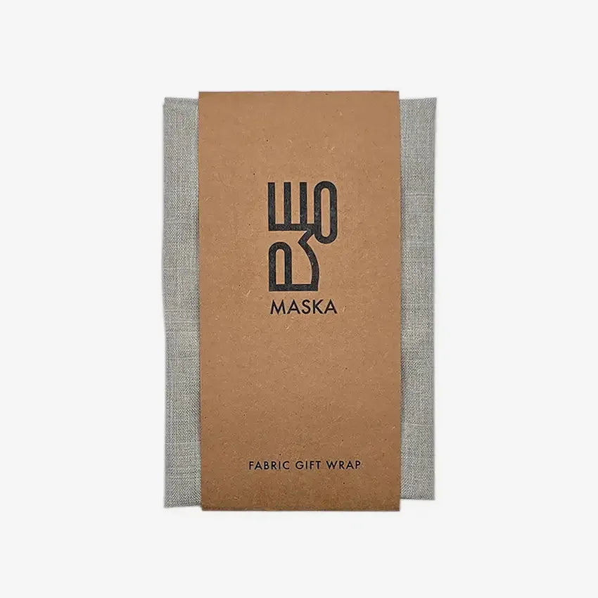 Grey poly cotton gift wrap folded with Maska kraft paper band, front view