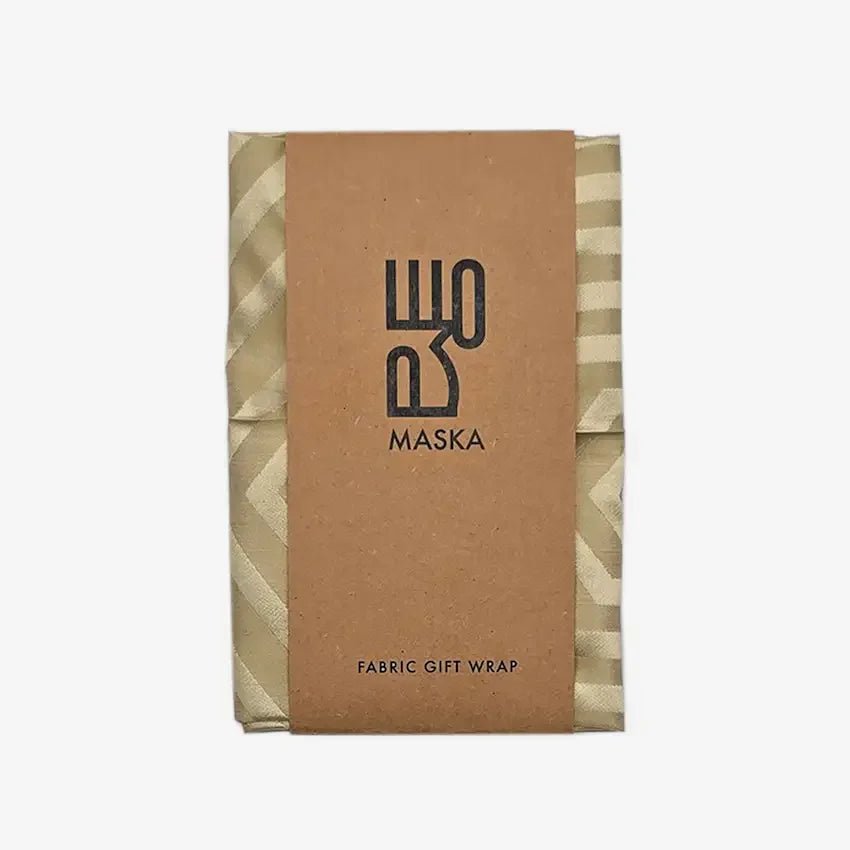 Folded sand striped fabric wrap with kraft Maska gift wrap band, front view
