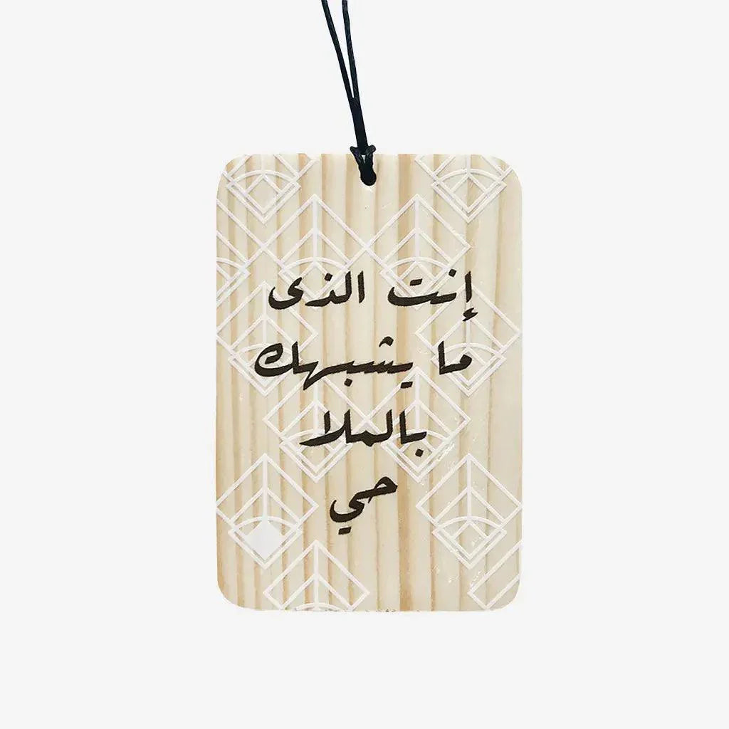 Wooden charm with Arabic calligraphy and geometric pattern, hanging on black cord