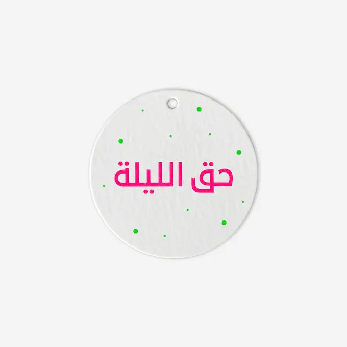 Round white gift tag with pink Hag El Laila script and green polka dots