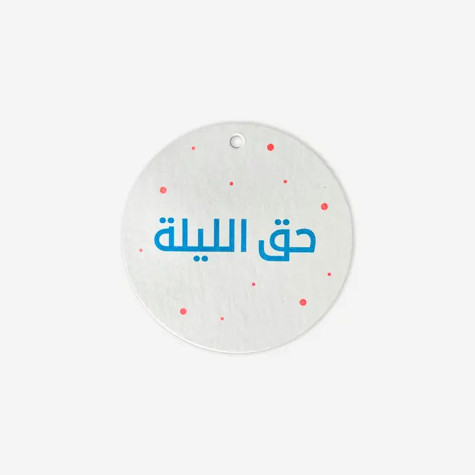 Round white gift tag with blue Hag El Laila script and pink dot pattern