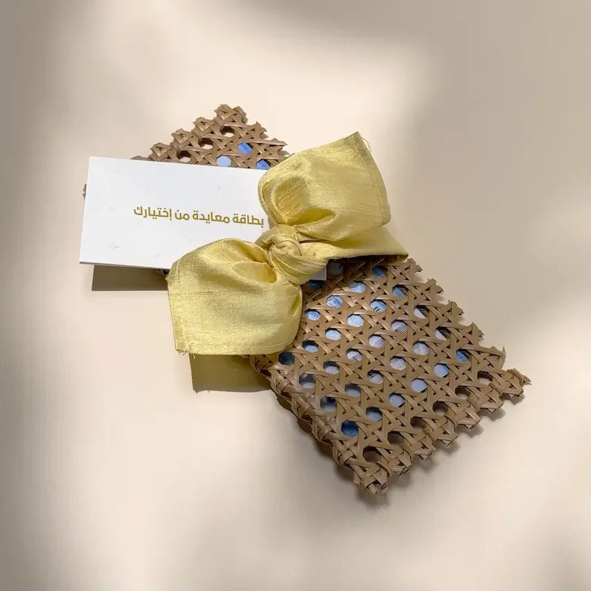 Rattan cash pouch tied with butter yellow fabric bow beside a blank greeting card