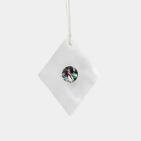 White diamond-shaped marble trinket with abalone shell centre on a hanging cord