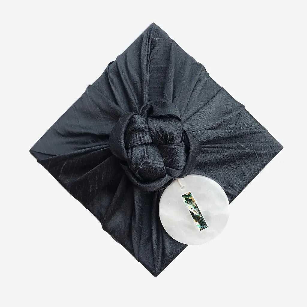 Marble trinket charm hanging from a black fabric gift wrap knot