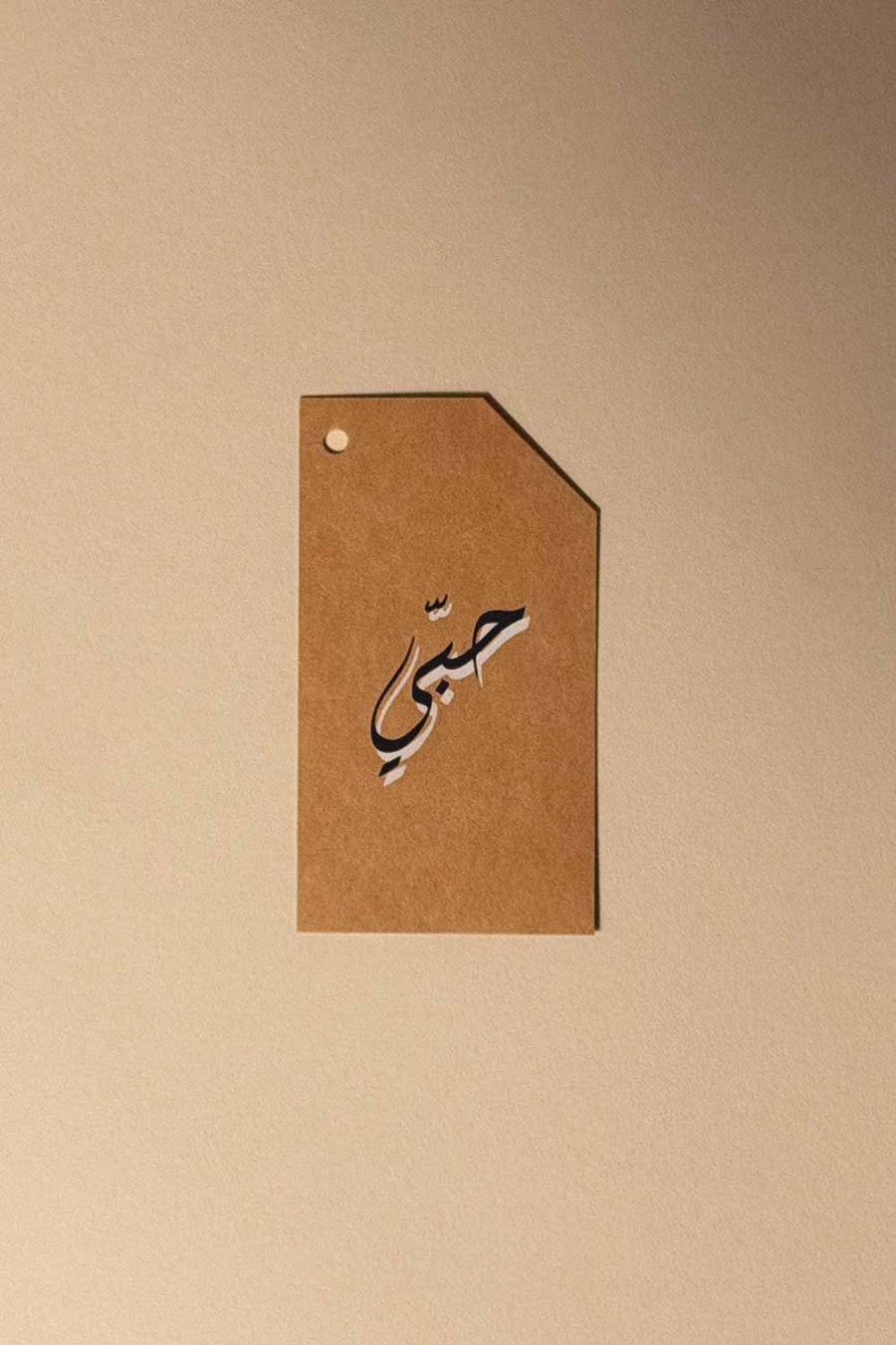 Kraft gift tag with Arabic calligraphy reading Hubbi, hole punched corner