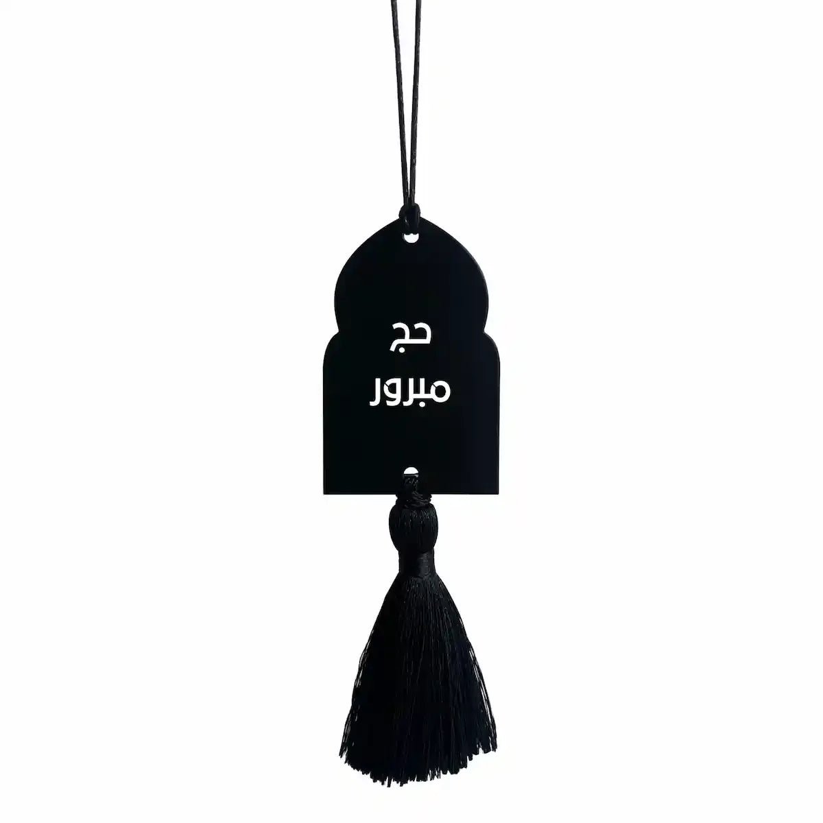 Black arch-shaped Hajj trinket with tassel, reading 'Hajj Mabroor' in Arabic