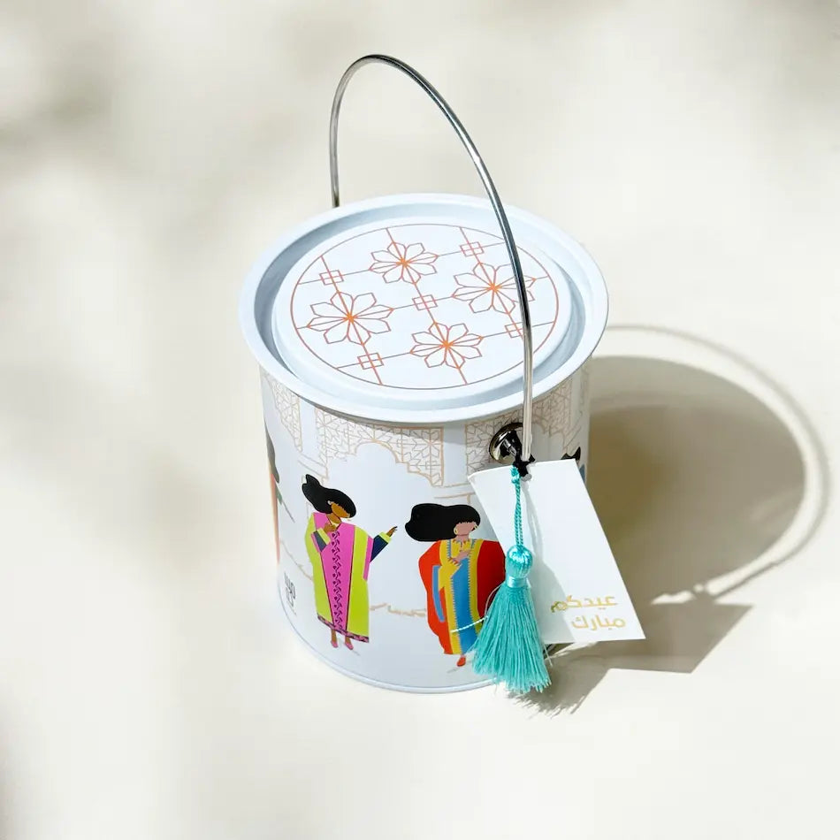 Overhead view of patterned tin can lid with wire handle and teal tassel charm