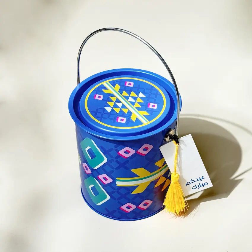 Blue Sadu tin bucket with lid closed, handle raised, Eid greeting tag attached