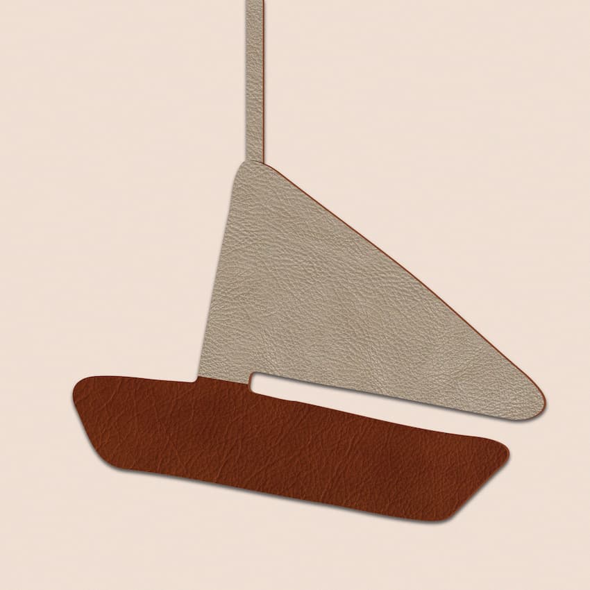 Close-up of leather sailboat charm in beige and tan, hanging