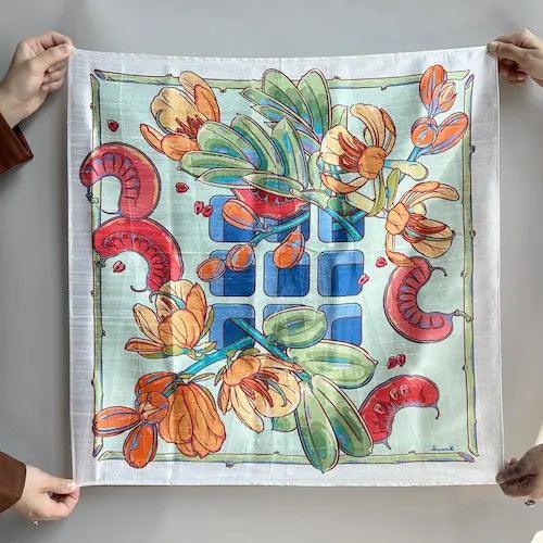 Printed fabric gift wrap held open showing floral and botanical pattern in coral and sage