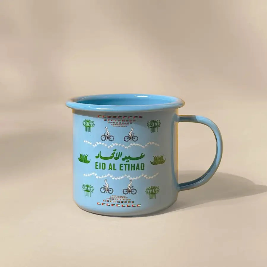 Light blue enamel mug with Eid Al Etihad print and cyclist design, side view