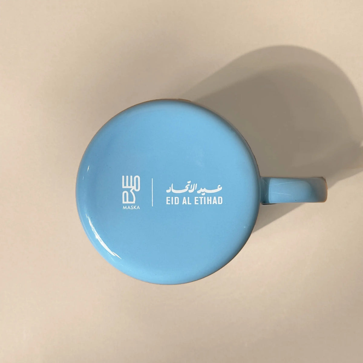 Top-down view of blue enamel mug showing Maska logo and Eid Al Etihad text