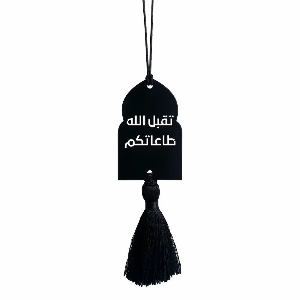 Black arch-shaped metal charm with Arabic acceptance phrase and tassel, hanging