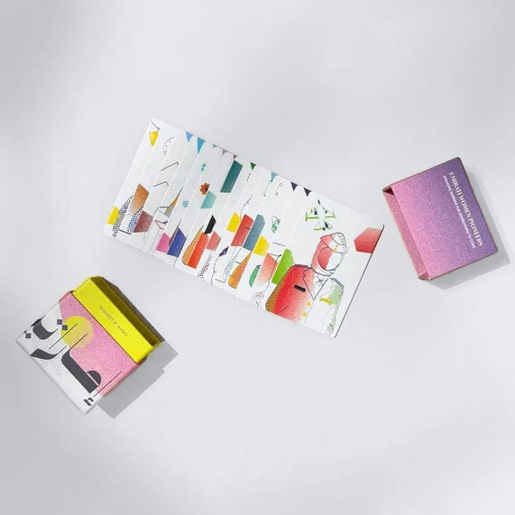 Fanned deck of colourful Emirati pioneer cards next to closed gift box