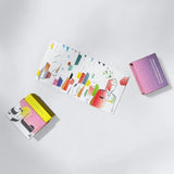 Fanned deck of colourful Emirati pioneer cards next to closed gift box