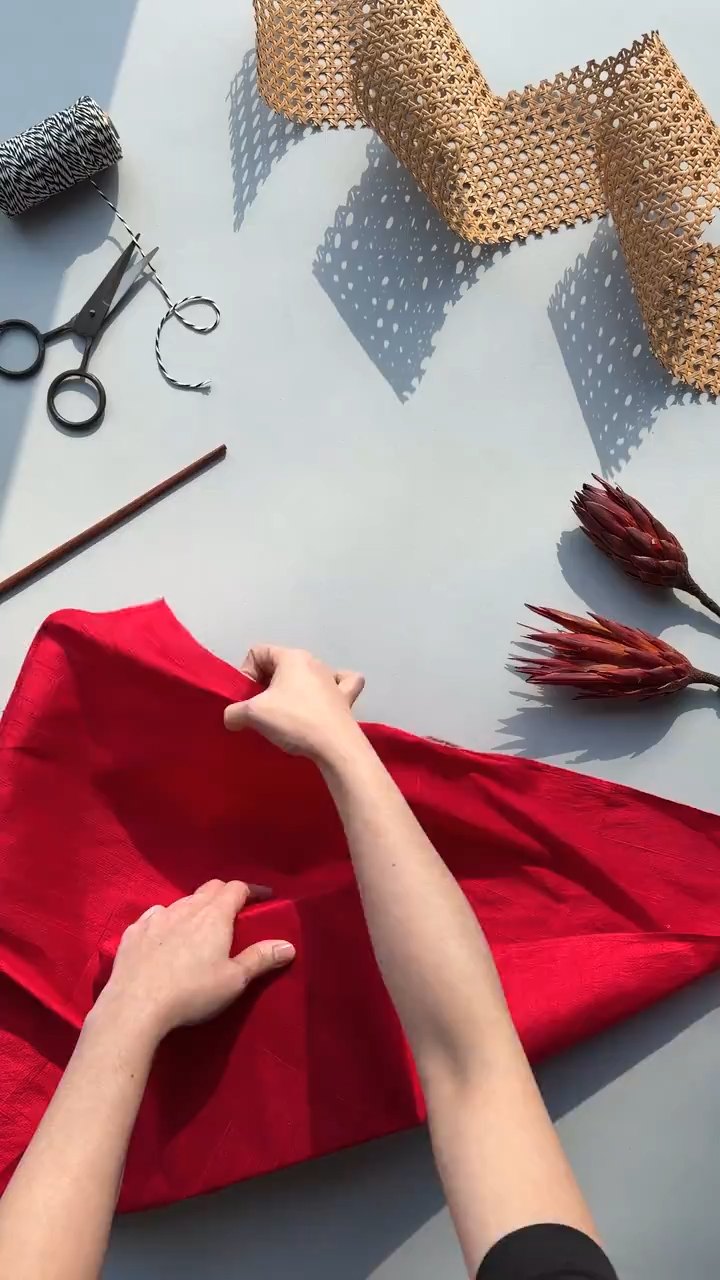 Hands wrapping a gift in red Maska fabric